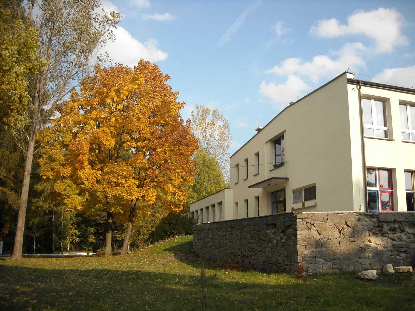 Budynek ośrodka MONAR w Lutej, z jasną elewacją i jesiennymi drzewami przy wejściu.