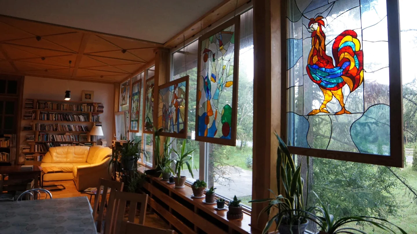 Wnętrze ośrodka MONAR w Milejowicach — sala z kolorowymi witrażami, roślinami i biblioteczką.