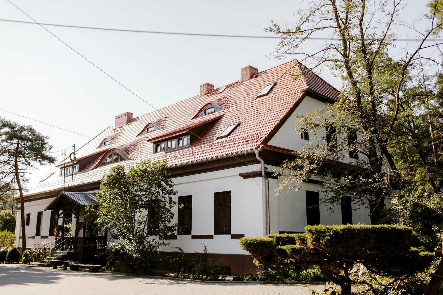 Budynek ośrodka MONAR w Zbicku z czerwonym dachem i drzewami przed wejściem.