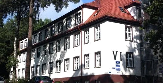 Budynek kompleksu Centrum Psychiatrii w Prabutach, biała elewacja i czerwony dach.