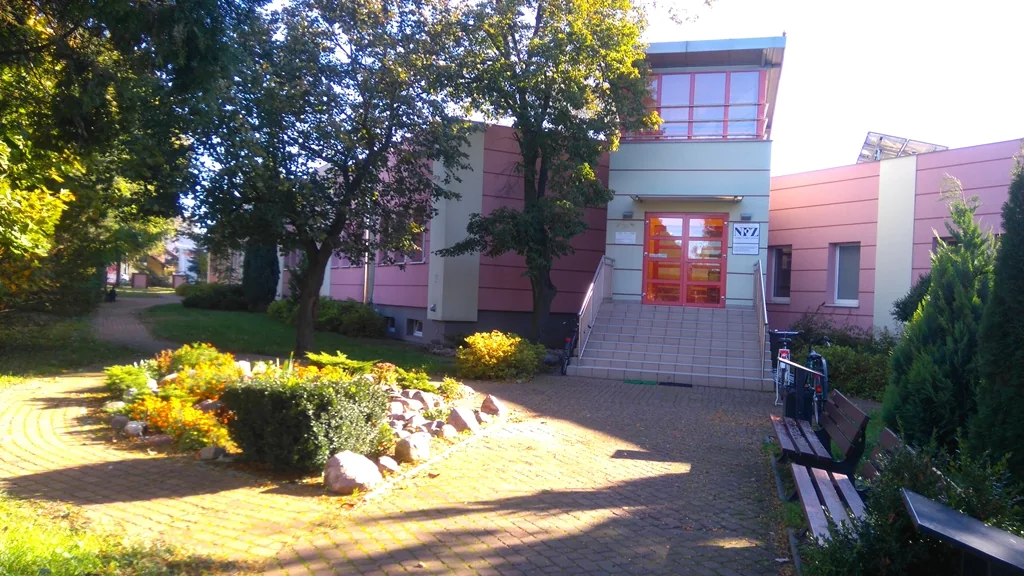 Wejście do Oddziału Leczenia Uzależnień I w Kościanie przy ul. Śmigielskiej 53, otoczone zielenią.