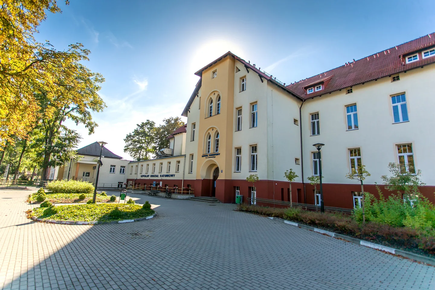 Zabudowania Szpitala Powiatowego w Złotowie przy ulicy Szpitalnej 28, z alejką i zielenią przed budynkiem.