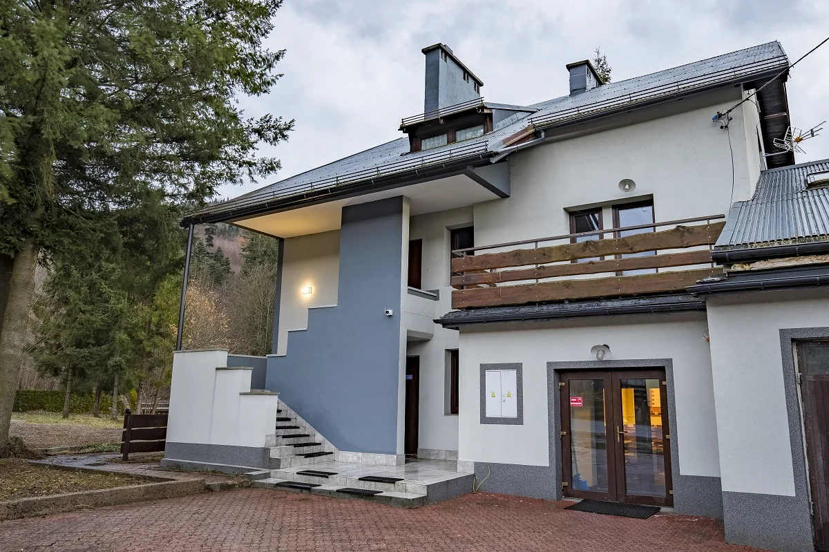 Budynek ośrodka Bezpieczna Przystań w Brennej — wejście, zewnętrzne schody i drewniany balkon.