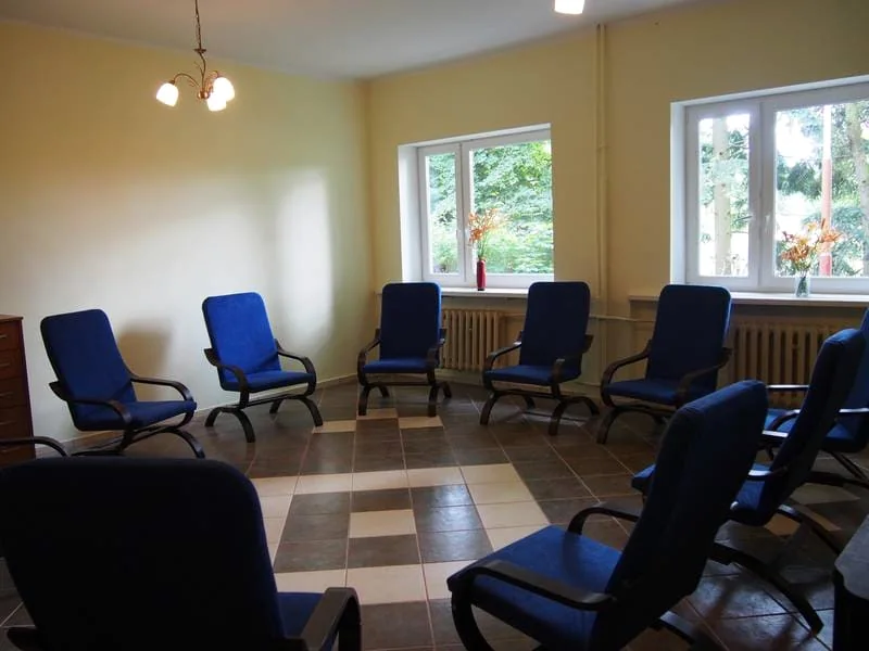 Sala w ośrodku Nowe Życie w Wapnicy — niebieskie fotele ustawione w kręgu.