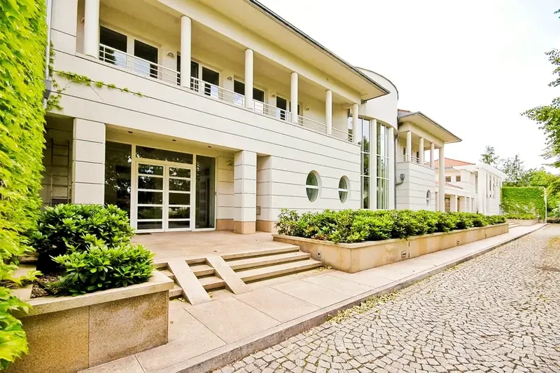 Wejście do ośrodka Zeus Detox & Rehab w Łomiankach Dolnych — jasna elewacja i krzewy przy podjeździe.
